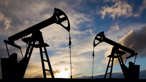 Oil Pump Jacks Silhouette Against Sunset Sky