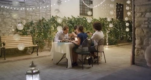 Friends Dining Together at Outdoor Celebration at Night