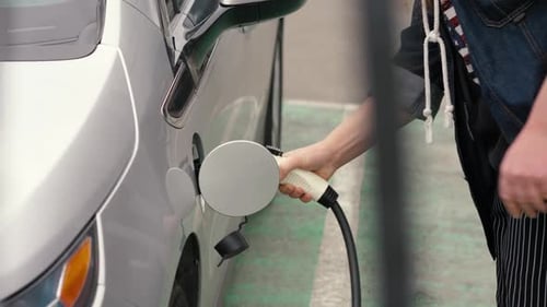 Woman Charging Electric Car in Urban Setting