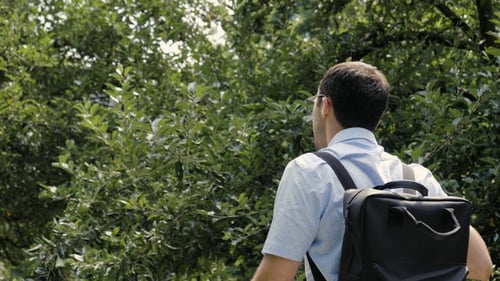 Man with Backpack Strolling Through Green Park