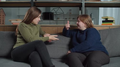 Women Talk on Couch and Gesture with Hands