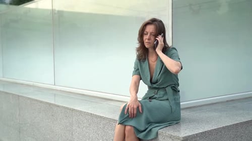 Unhappy Sorrowful Woman Is Calling By Mobile Phone on Street, Touching Forehead By Hand