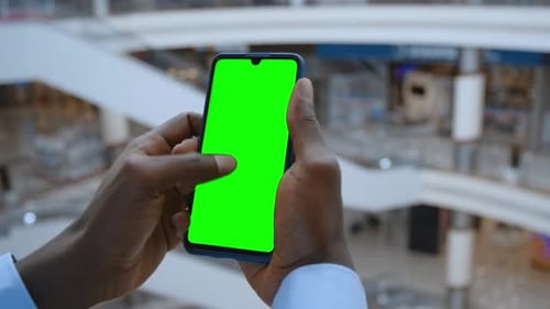 Handkamera: Sichtweise eines Mannes im Einkaufszentrum mit Telefon mit grünem Mock-up-Bildschirm