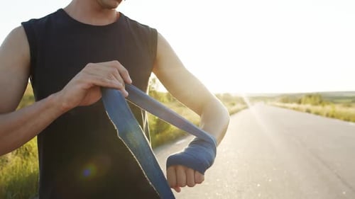 Close View of Sportsman Wrapping Hand Into Tape at Camera Outdoors