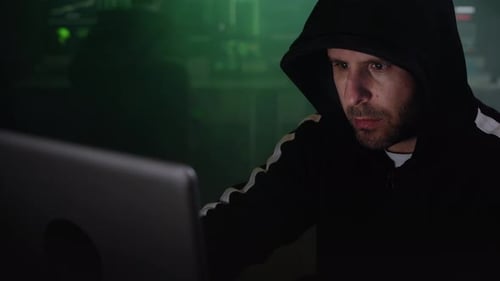 Man in Hoodie Working on Computer in Dark