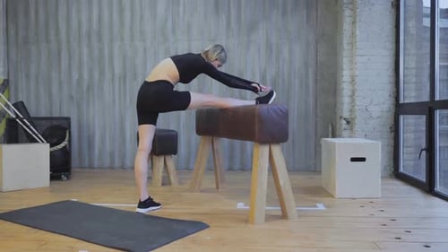 Sporty young woman exercising on gymnastic bars in fitness gym. Stretching exercises, regular sport