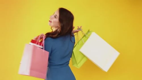 Woman Smiling Holding Shopping Bags on Yellow Background