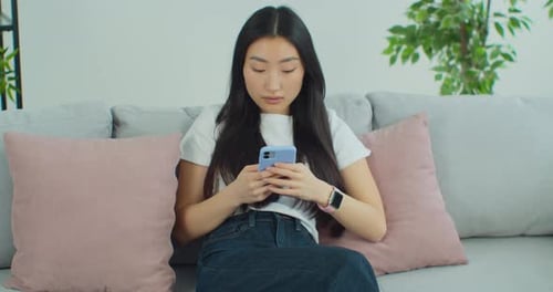 Young Woman Using Mobile Phone on Couch