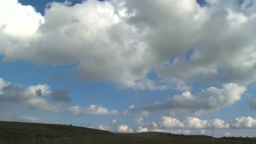 Time lapse of clouds over rural landscape with green hills