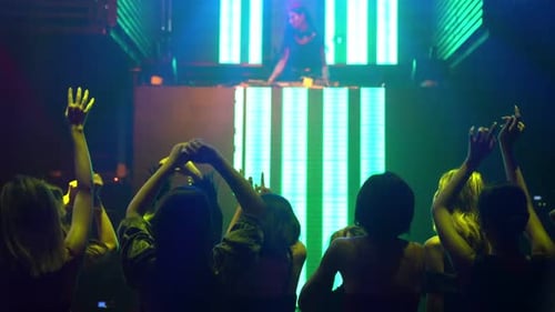 Eine Gruppe von Menschen tanzt im Disco-Nachtclub zum Takt der Musik eines DJs auf der Bühne
