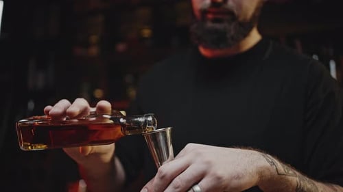 Barkeeper misst flüssige Cocktailzutat mit Jigger
