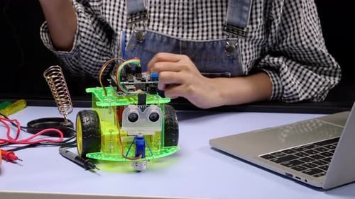 Ingénieurs en robotique ou étudiant soudant la puce d'un circuit imprimé sur une voiture robot.