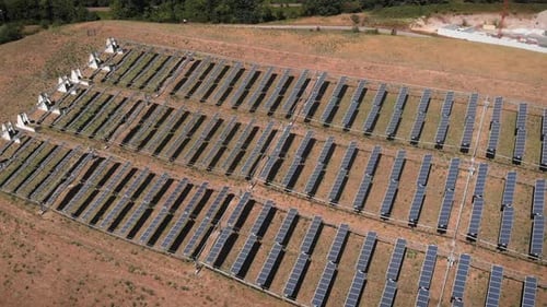 Flying over large solar panels at solar farm at sunny summer day