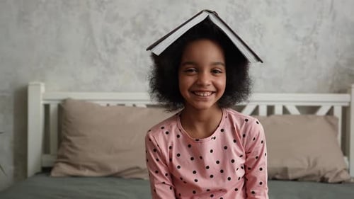 Happy Child Balances Book on Head at Home