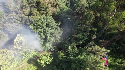 Smoke Rises From Forest Beside Parked Firetruck