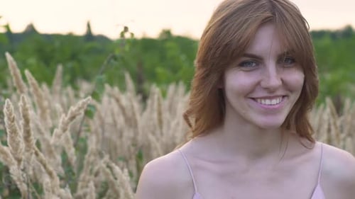 Closeup Portrait of a Young Attractive Redhaired Woman in a Field with Spikelets