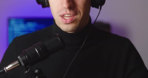 Closeup of Male Blogger in Headphones Talking in Microphone Recording Podcast in Studio