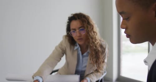 Biracial female architects talking and checking architects plans in modern office