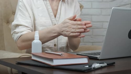 Woman Sanitizes Hands Before Typing on Computer