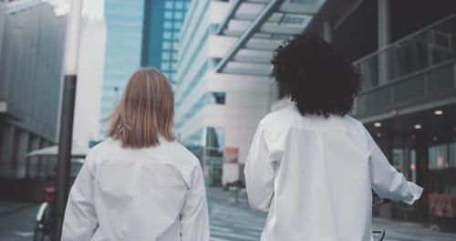 Two young women in business attire walk away with a bike in a business area