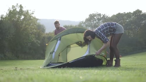 Couple Assembling Tent on Grassy Field