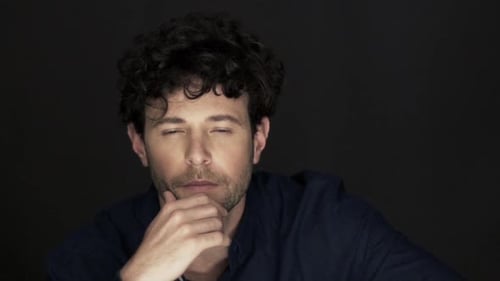 Man Thinking Seriously in Close-Up Against Black