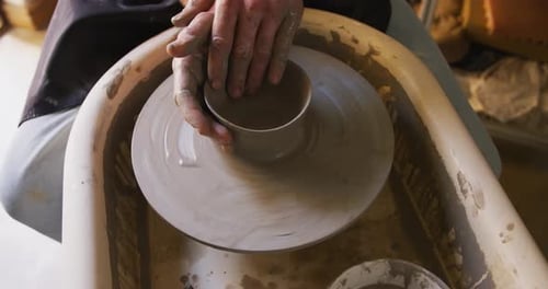 Close up view of male potter creating pottery on on potters wheel at pottery studio