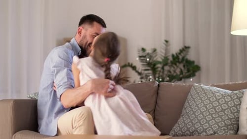 Playful Father Tickling Daughter on Couch at Home