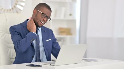Tired African Businessman with Laptop Having Neck Pain in Office