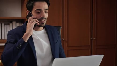 Man Works at Desk, Answers Smartphone