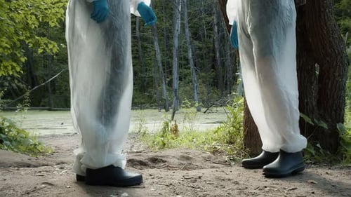 Scientists in Protective Suits Near Swamp