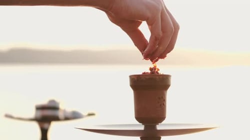 Preparing the Hookah with Ocean Sunset Background