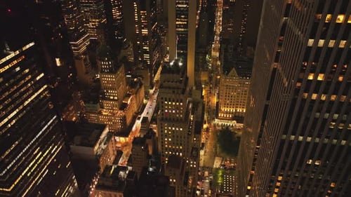 Cars Driving on Street Between High Rise Buildings in Night City