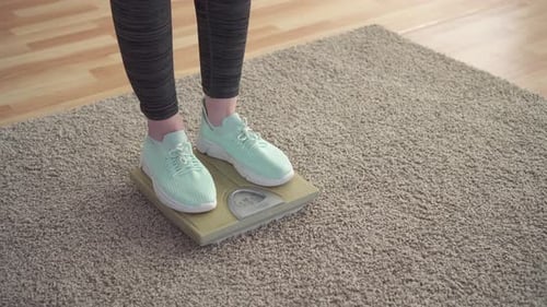 Woman Weighing Herself on Bathroom Scale