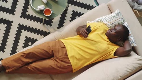 Man Relaxing on Sofa Using Smartphone, Top View