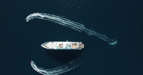 Aerial view of two Jet Ski Zooming heart around Super Yacht at Sunset. Heart round the super yacht