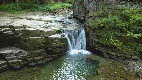 Wasserfall am Gebirgsfluss mit weißem, schaumigem Wasser, das im Sommer von einer Felsformation herunterfällt