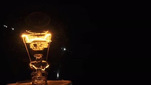 Wolfram-Filament in einer Glaslampe Nahaufnahme in Zeitlupe auf schwarzem Hintergrund