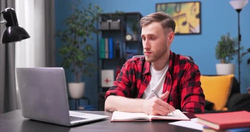 A Focused College Student Boy is Video Chatting on a Laptop