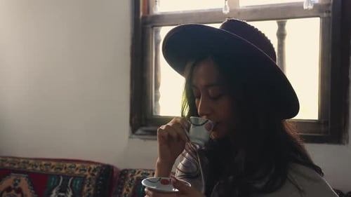 Woman Wearing Hat Drinking Coffee by a Window
