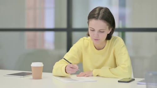 Young Woman Writing on Paper in Office