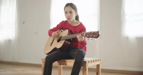 Young Girl Plays Acoustic Guitar in Bright Room