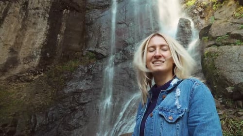 A young traveler smiled at the camera and enjoyed the wildlife with a waterfall