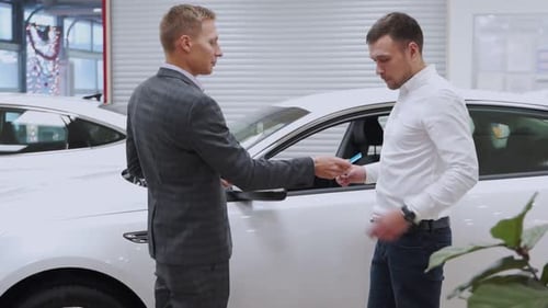 Man Hand Gives a Car Keys To Male Hand in the Car Dealership Close Up. Auto Seller and a Man Who