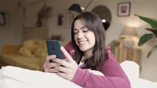 Woman Smiling While Using Cell Phone Indoors