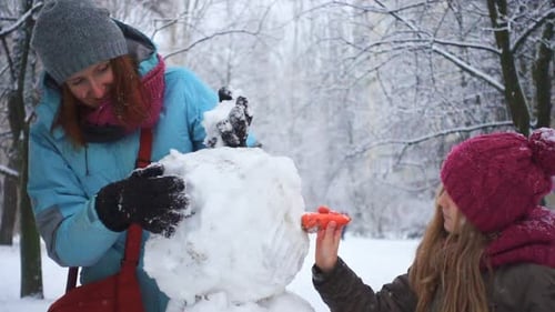 Mother and Child Building Snowman in Winter Wonderland