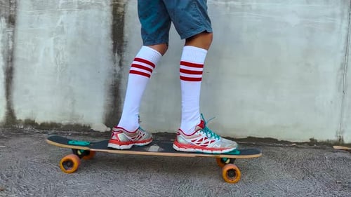 Cheerful Little Boy with Long Wavy Hair in Rides on a Long Skateboard