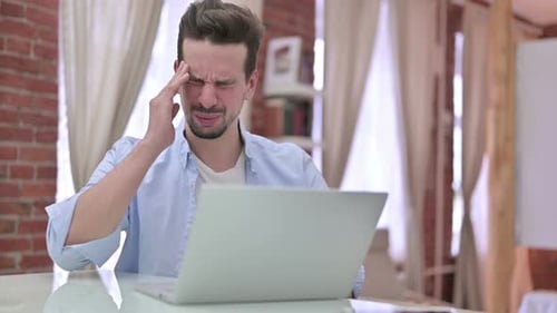 Man Working on Laptop with Headache