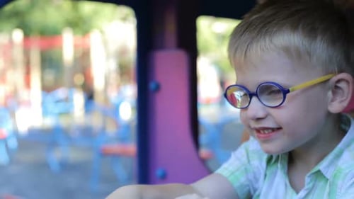 A little boy is played on the playground in a toy car.