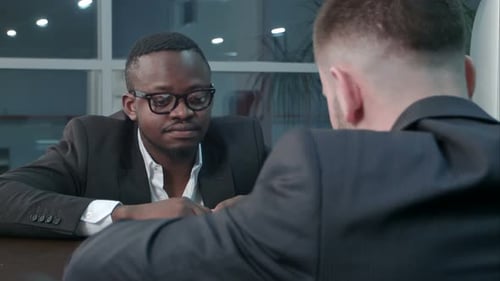 Pensive Afro-american and Caucasian Businessmen Working Through Papers and Discussing Financial